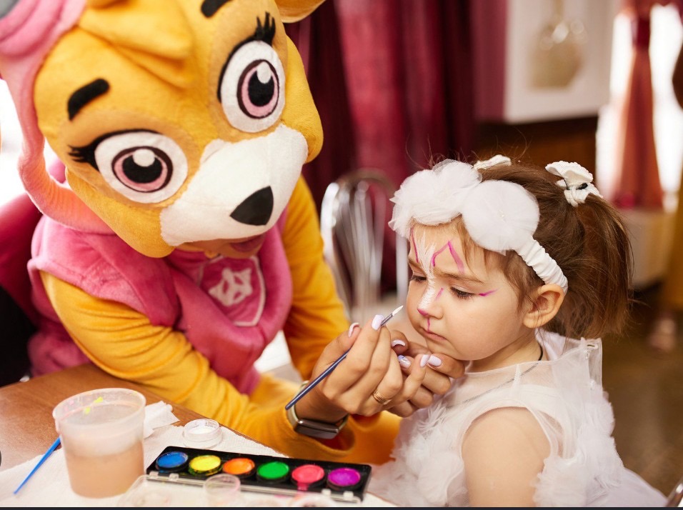 Kids entertainer in a character costume painting a child's face at a Phuket party